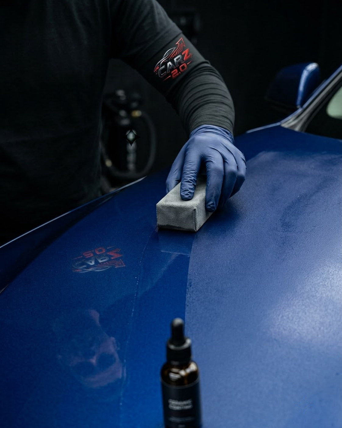 Detailing specialist applying ceramic coating to a graphite car hood