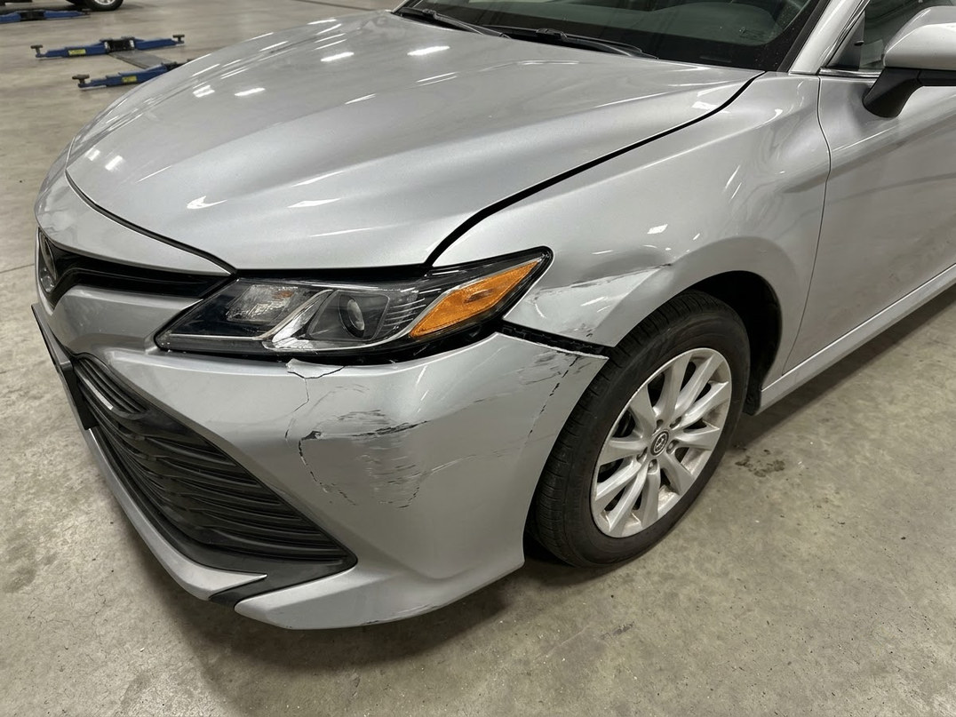 Damaged vehicle being assessed in a workshop bay