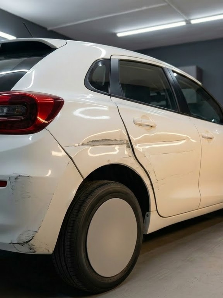 White hatchback with a creased rear quarter panel and scuffed bumper