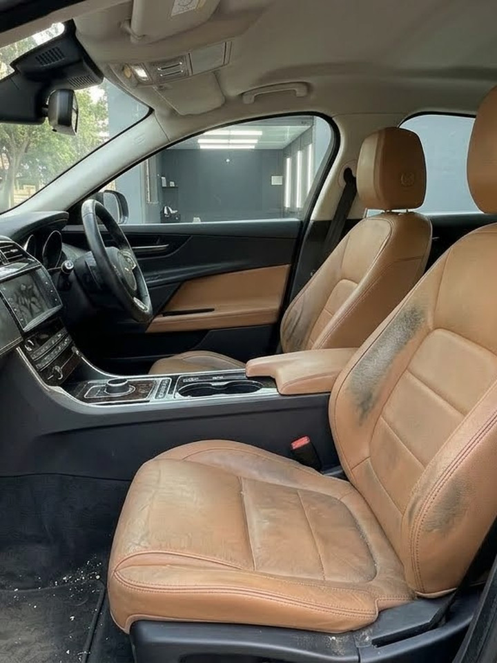Tan leather cabin with soiled seats and a dusty dashboard
